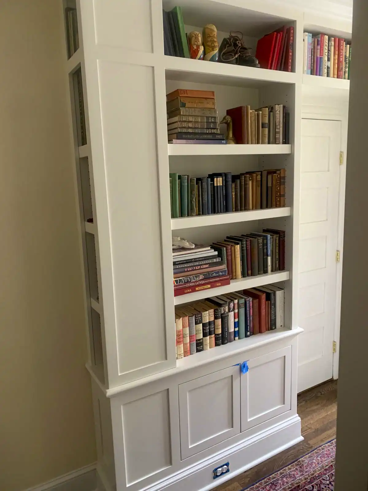 White built-in bookshelf with lower cabinet doors and painted trim.