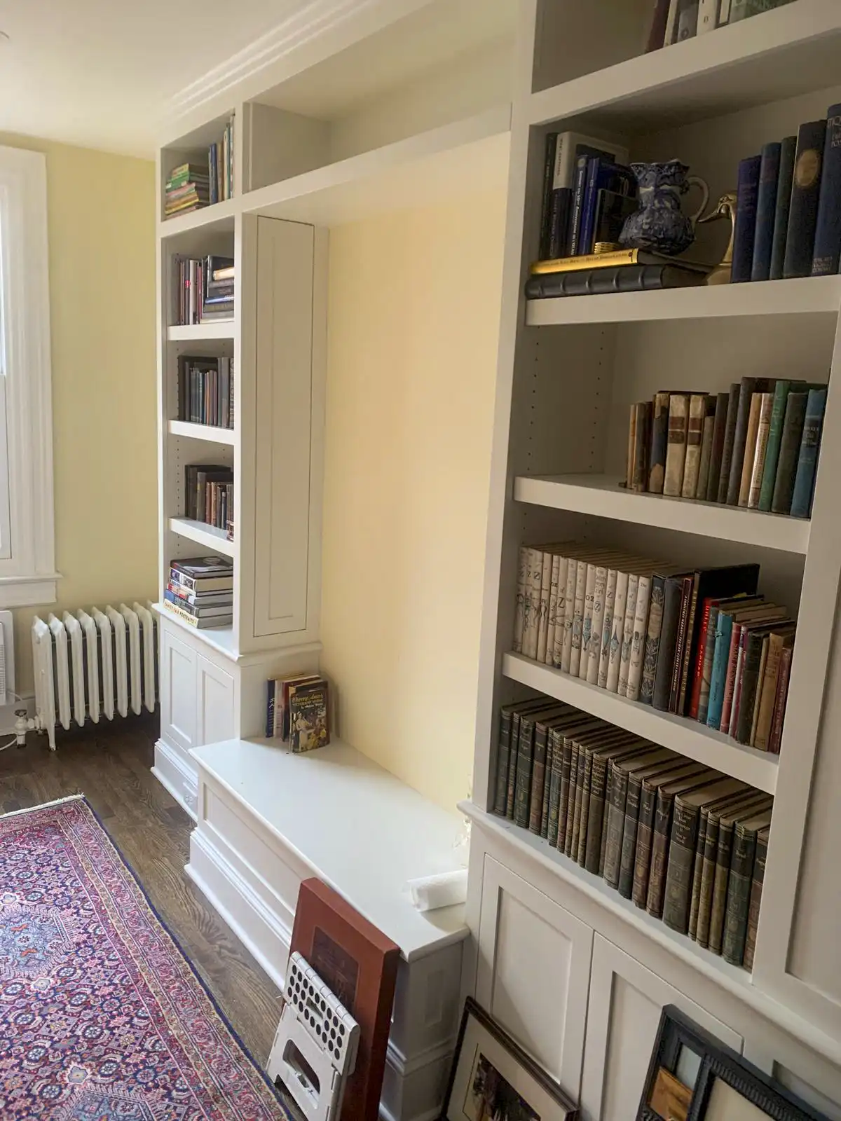 White built-in bookshelves with lower cabinets and a window seat.