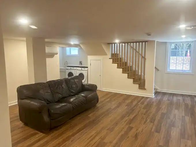 Interior with wood-look flooring, recessed lighting, a sofa and a staircase.