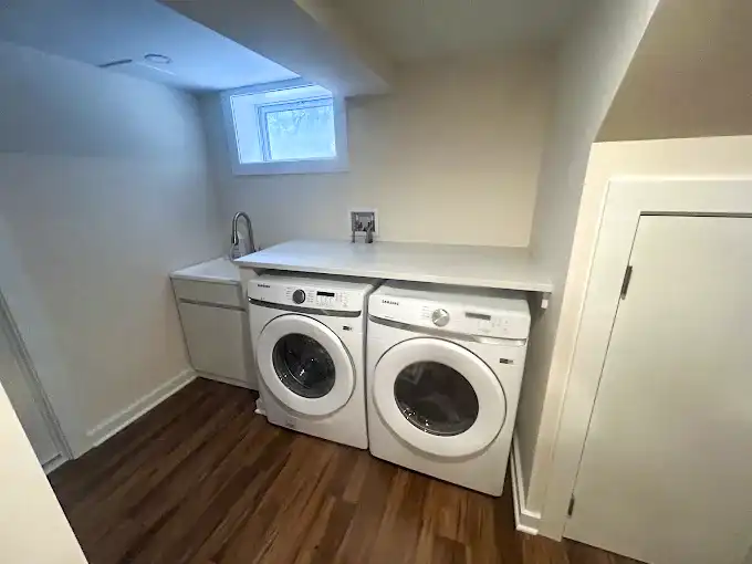 Laundry area with a washer, dryer, countertop and wood-look flooring.