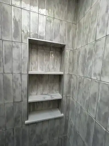 Recessed tiled shelves set into a gray bathroom wall.