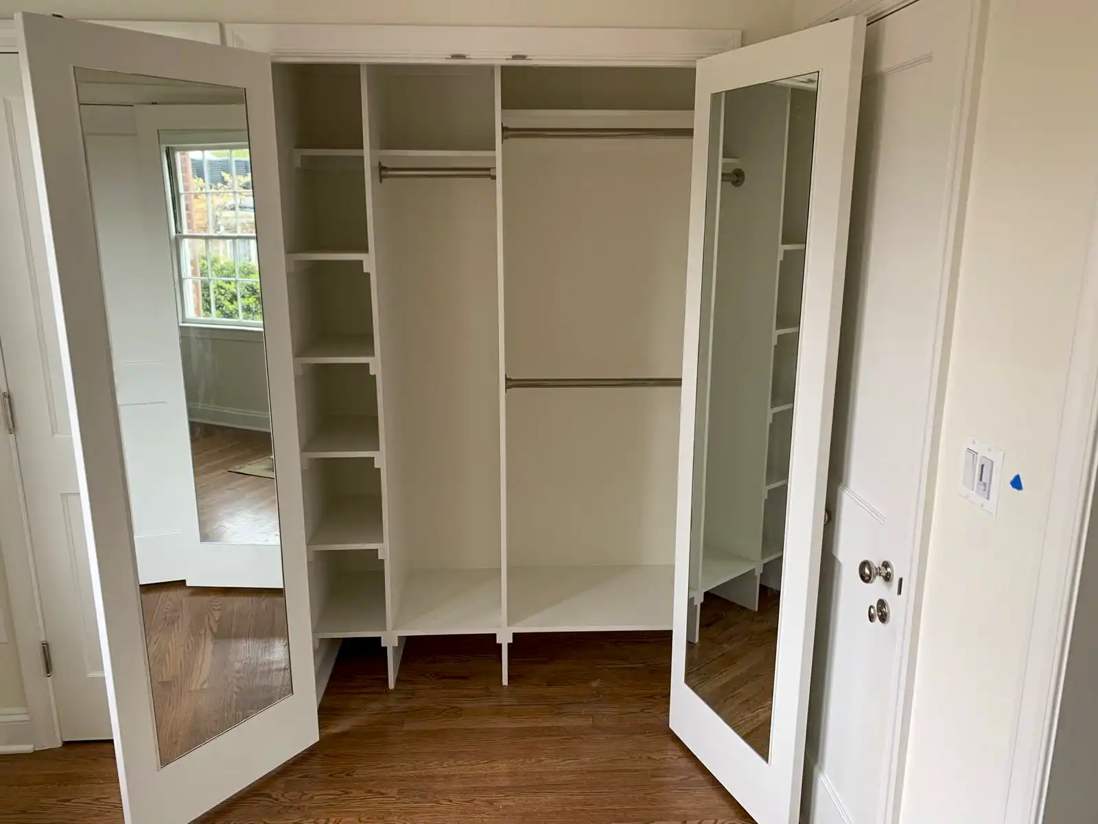 White fitted wardrobe with open shelves, hanging rails and mirrored doors.